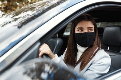 young-woman-driver-sitting-in-car-driving-to-work-in-face-mask-min